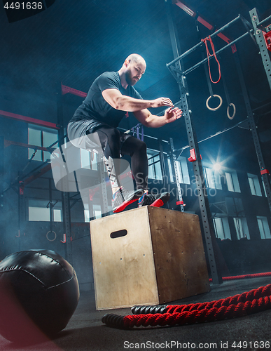 Image of Man jumping during exercises in the fitness gym. CrossFit.