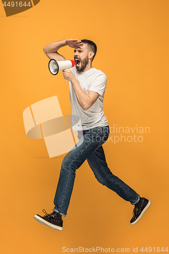 Image of Jumping fan on orange background. The young man as soccer football fan with megaphone