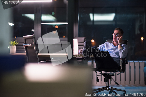 Image of businessman using mobile phone in dark office