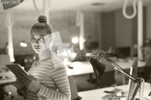 Image of woman working on digital tablet in night office