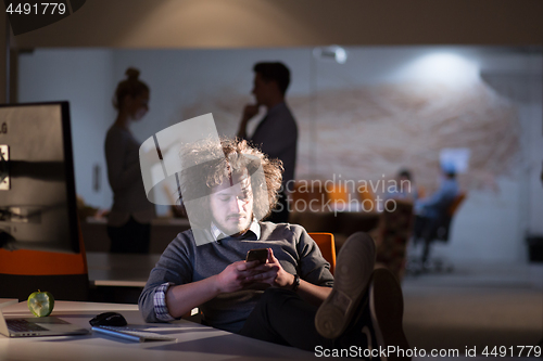 Image of businessman sitting with legs on desk at office