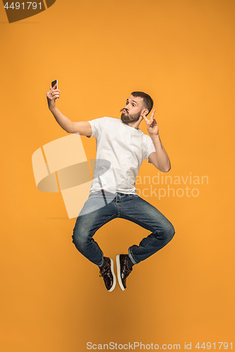 Image of Time to take selfie. Full length of handsome young man taking selfie while jumping