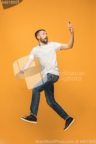 Image of Full length of handsome young man taking selfie while jumping