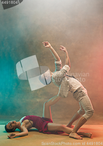 Image of Flexible young modern dance couple posing in studio.