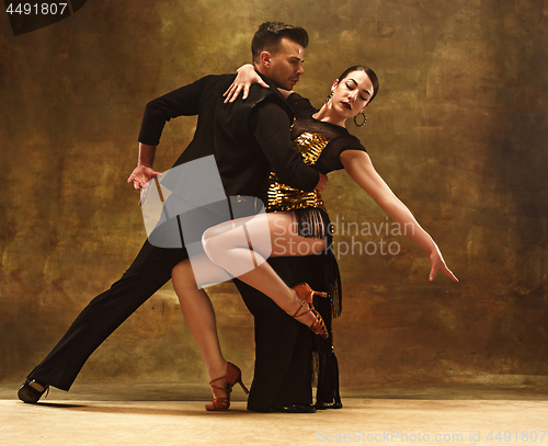 Image of Dance ballroom couple in gold dress dancing on studio background.