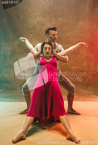 Image of Flexible young modern dance couple posing in studio.