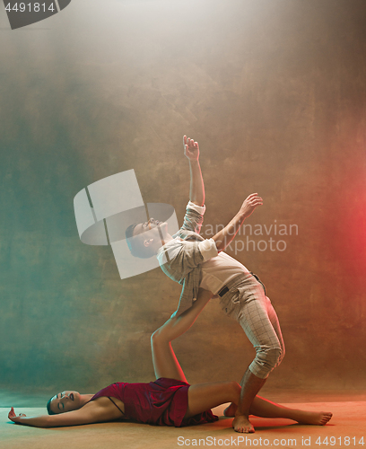 Image of Flexible young modern dance couple posing in studio.