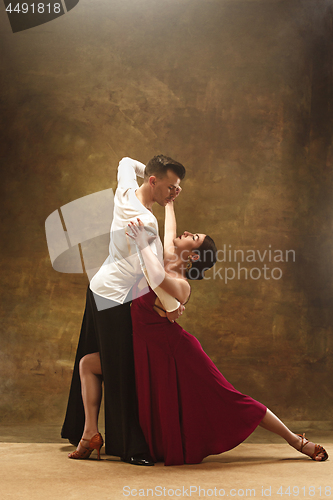 Image of Dance ballroom couple in red dress dancing on studio background.