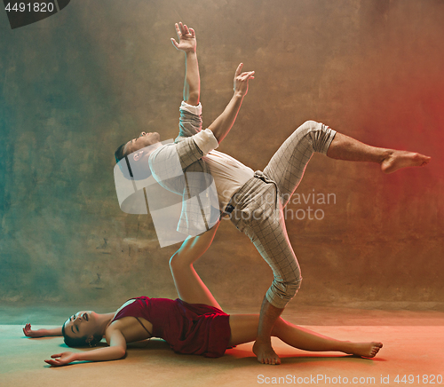 Image of Flexible young modern dance couple posing in studio.