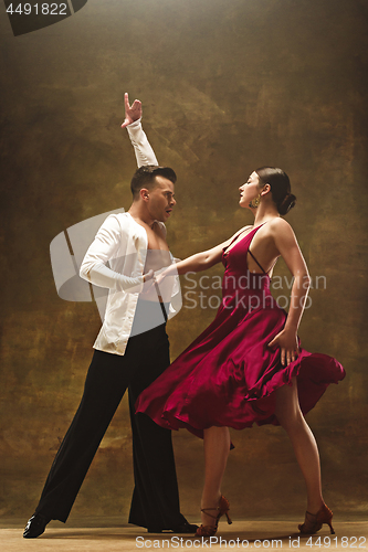 Image of Dance ballroom couple in red dress dancing on studio background.