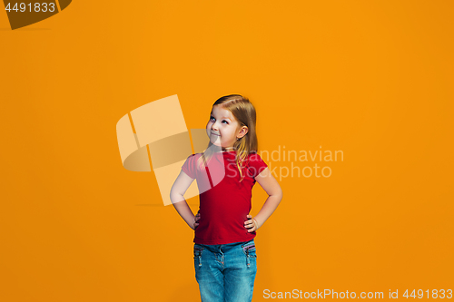 Image of The happy teen girl standing and smiling against orange background.