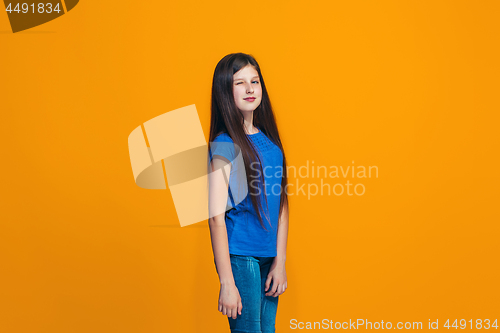 Image of The happy teen girl standing and smiling against orange background.