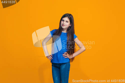 Image of The happy teen girl standing and smiling against orange background.