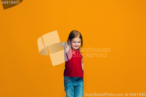 Image of The happy teen girl pointing to you, half length closeup portrait on orange background.