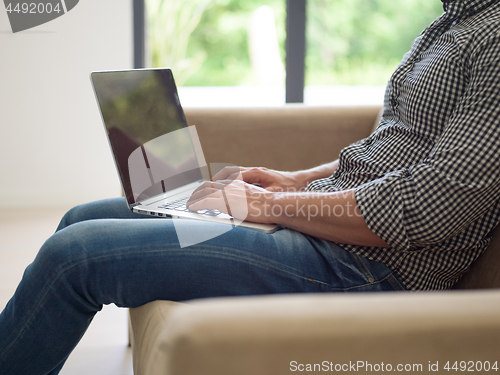 Image of Man using laptop in living room