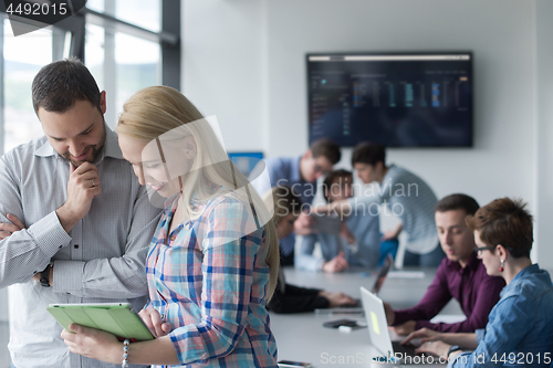 Image of Two Business People Working With Tablet in office