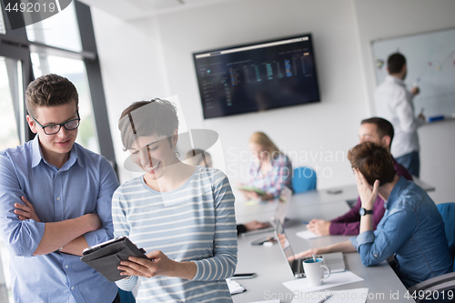 Image of Two Business People Working With Tablet in office