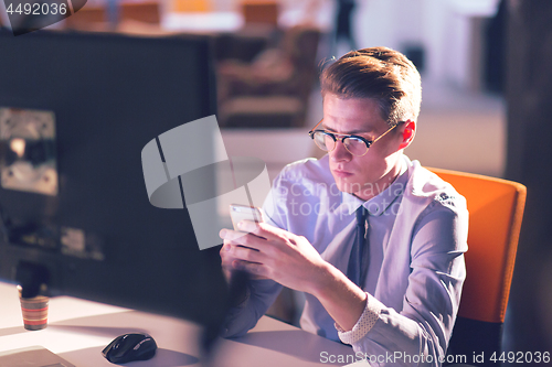 Image of man using mobile phone in dark office