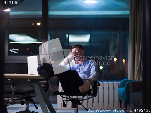 Image of businessman sitting with legs on desk at office