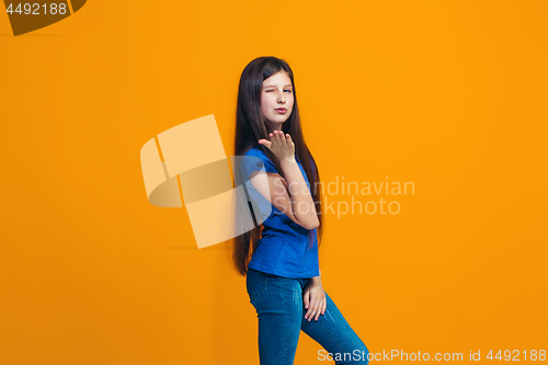 Image of The happy teen girl standing and smiling against orange background.