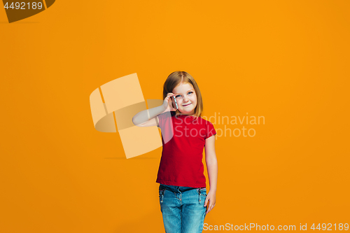 Image of The happy teen girl standing and smiling against orange background.