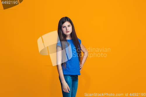 Image of The happy teen girl standing and smiling against orange background.