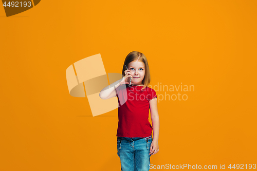 Image of The happy teen girl standing and smiling against orange background.