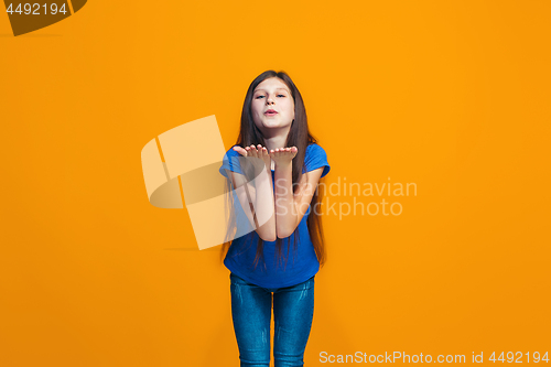 Image of The happy teen girl standing and smiling against orange background.