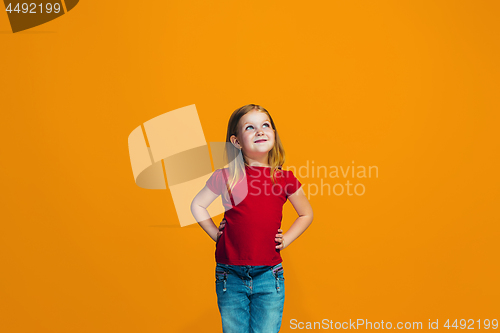 Image of The happy teen girl standing and smiling against orange background.