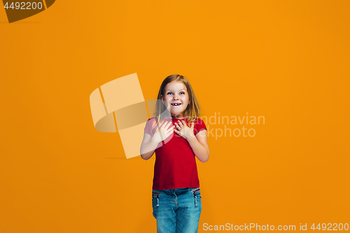 Image of The happy teen girl standing and smiling against orange background.