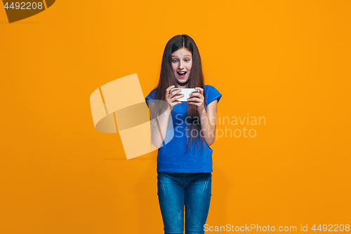 Image of The happy teen girl standing and smiling against orange background.