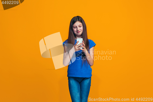 Image of The happy teen girl standing and smiling against orange background.