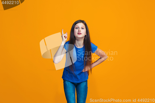 Image of Beautiful female half-length portrait on orange studio backgroud. The young emotional teen girl