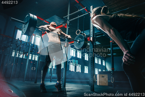 Image of Fit young man lifting barbells working out in a gym