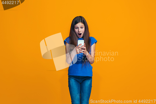 Image of The happy teen girl standing and smiling against orange background.