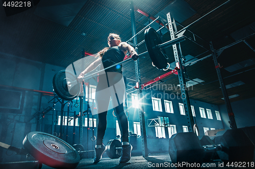 Image of Fit young woman lifting barbells working out in a gym