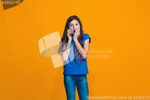 Image of The happy teen girl standing and smiling against orange background.