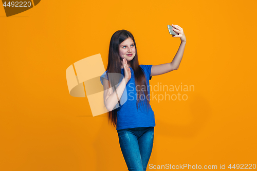 Image of The happy teen girl standing and smiling against orange background.