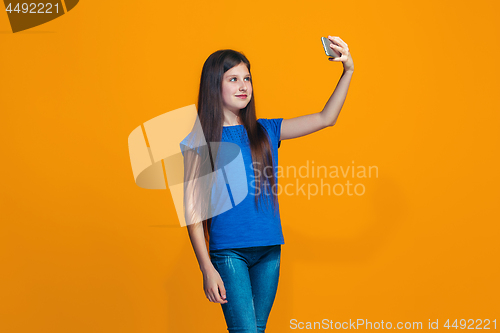 Image of The happy teen girl standing and smiling against orange background.