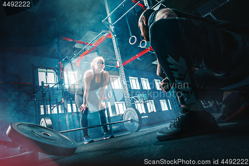 Image of Fit young woman lifting barbells working out in a gym