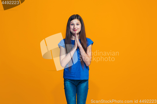 Image of Beautiful teen girl looking suprised isolated on orange