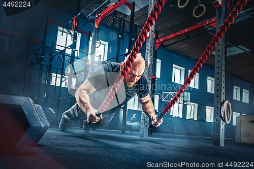 Image of Men with battle rope battle ropes exercise in the fitness gym.