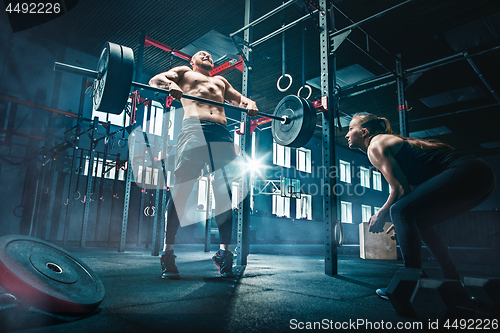 Image of Fit young man lifting barbells working out in a gym