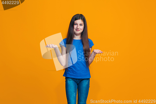 Image of Beautiful teen girl looking suprised and bewildered isolated on orange