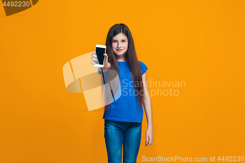 Image of The happy teen girl standing and smiling against orange background.