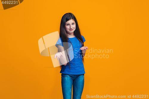 Image of Beautiful teen girl looking suprised and bewildered isolated on orange