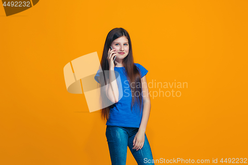 Image of The happy teen girl standing and smiling against orange background.