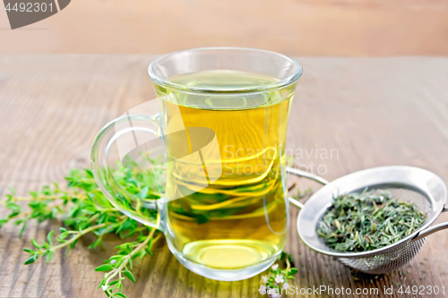 Image of Tea of thyme in mug with strainer on wooden board