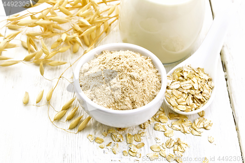 Image of Flour oat in bowl with milk on white wooden board