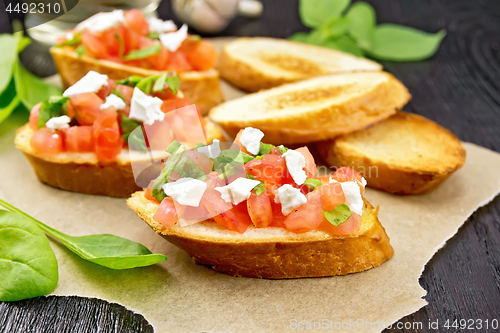 Image of Bruschetta with tomato and cheese on dark board